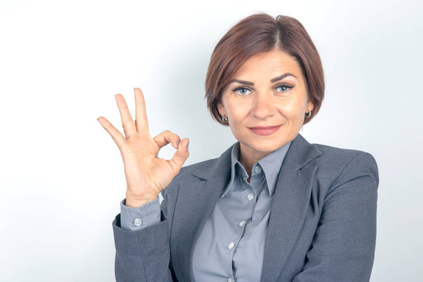 Business woman in suit shows ok sign with hands - 写真・画像