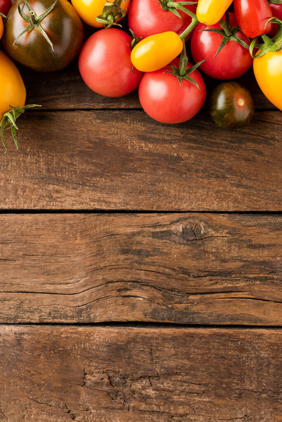 Overhead shot of mixed tomatoes on rustic wooden background with copyspace. Top view - Fotó, kép