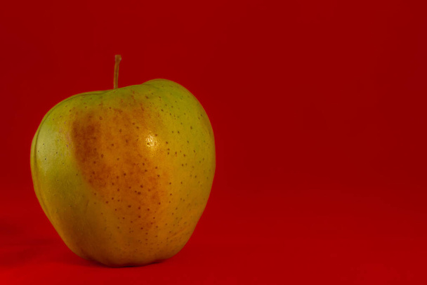 egy sárga alma, piros háttérrel, ideális háttérképek - Fotó, kép