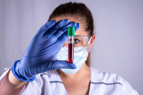 Bioquímico con un tubo de sangre en la mano. tubo sanguíneo Bioquímico mirando un tubo de sangre. Bioquímico analizando un tubo con sangre - Foto, Imagen