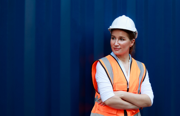 Portrait of an employee or supervisor Smiling caucasian female container worker wearing a white hard hat. The concept behind the success and movement of industrial goods, logistics, import-export. - Photo, image