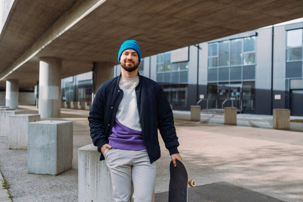 Stylish smiling skater holding longboard. Happy Caucasian man wearing casual clothes. Copy space - Foto, Imagen