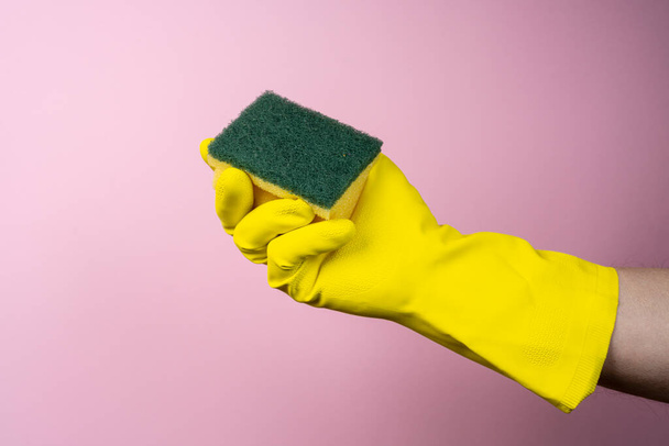 uma mão com uma luva de borracha amarela segura uma esponja de limpeza - Foto, Imagem