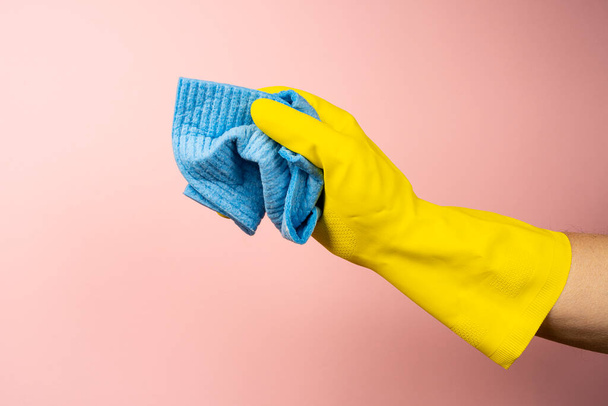 une main avec un gant en caoutchouc jaune tient une éponge nettoyante - Photo, image