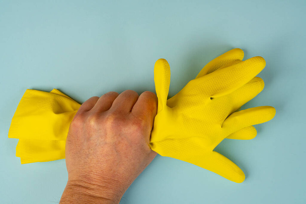 one hand holds two yellow rubber cleaning gloves - Photo, image