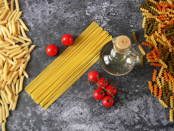 Various types of pasta, Raw pasta set and tomato on wooden background, set, closeup - Photo, Image