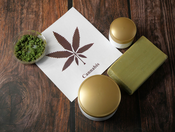 Crema di cannabis cosmetica in dose con pianta di marijuana su fondo di legno. Concetto di cosmetici a base di cannabis. Primo piano - Foto, immagini
