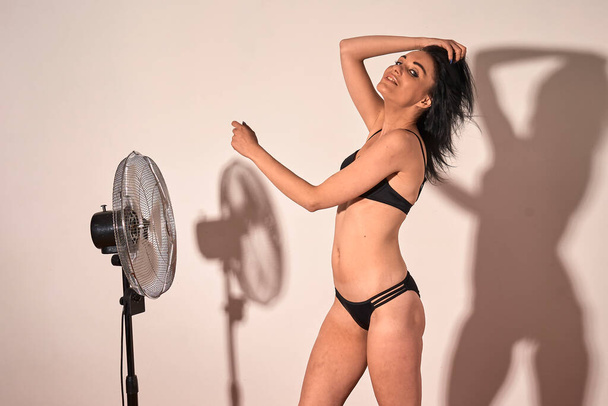 Girl wear bikini, posing in studio nice shadow of girl and fan at background - Photo, image