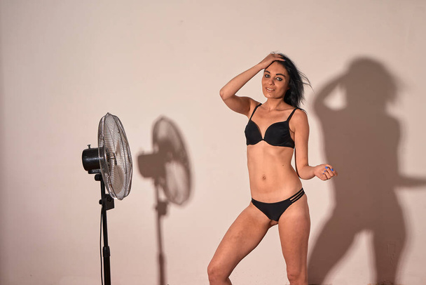 Girl wear bikini, posing in studio nice shadow of girl and fan at background - Fotó, kép