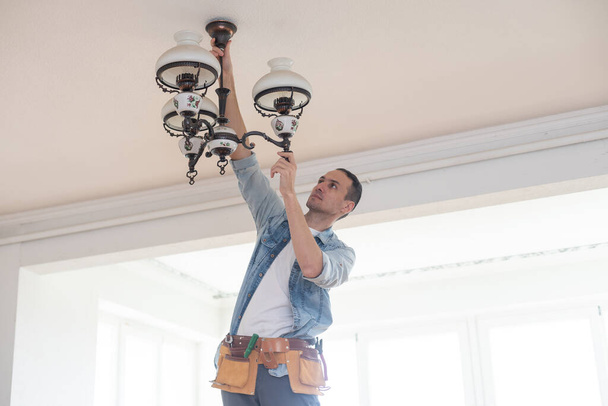 Reparador o electricista profesional en ropa de trabajo instalando puntos de luz - Foto, imagen