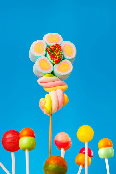 Multi-gekleurde snoepjes op een stok, blauwe achtergrond.Veel kleurrijke lolly 's (Chyupa-Chyups) op een blauwe achtergrond - Foto, afbeelding