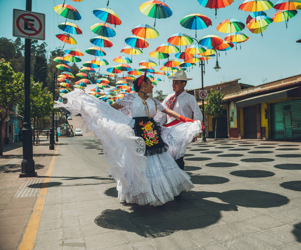 Tänzer typischer mexikanischer Tänze aus der Region Veracruz, Mexiko, bei ihrer Performance auf der mit bunten Regenschirmen geschmückten Straße. - Foto, Bild