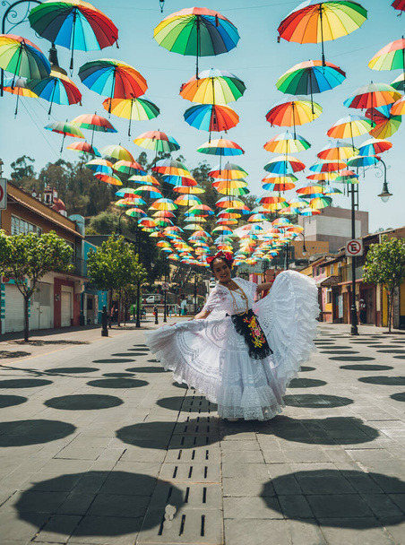 Χορεύτρια τυπικών μεξικάνικων χορών από την περιοχή Veracruz του Μεξικού, κάνοντας την παράστασή της στο δρόμο στολισμένη με χρωματιστές ομπρέλες. - Φωτογραφία, εικόνα