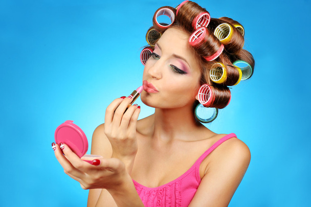 Beautiful girl in hair curlers on blue background - Foto, Imagen