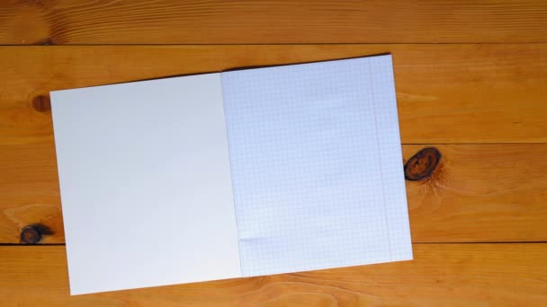 School teacher lays out a checkered notebook for mathematics, ruler, triangle, protractor, pen, pencil on a wooden table in the school classroom. Copy space for text. Blank sheet math page. Top view - Footage, Video