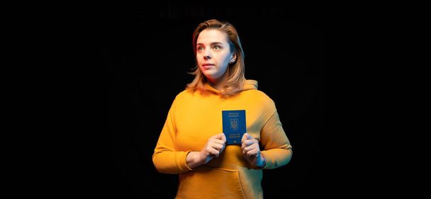 ウクライナ国民のパスポート。美しいですウクライナの女の子とともに政府パスポートで彼女の手に黒の背景. - 写真・画像
