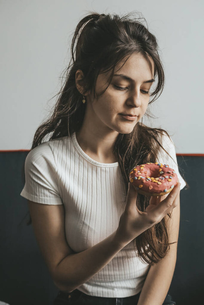 Close up portrait of pleased pretty girl eating donuts - Fotó, kép
