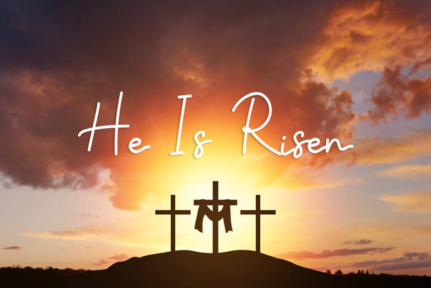 Sonntag ist er auferstanden. Kalvarienberg und drei Silhouetten von Kreuzen bei Sonnenaufgang., mit Text Er ist auferstanden - Foto, Bild