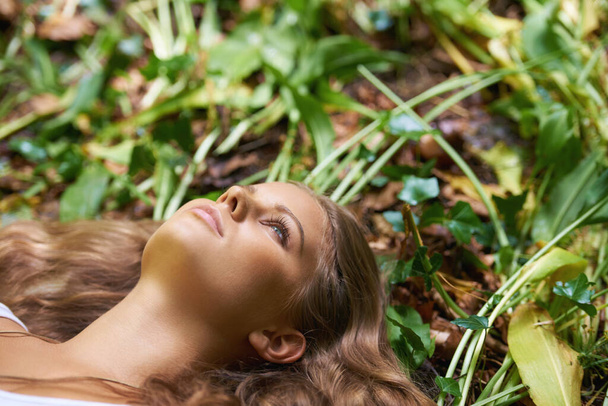 Επιστρέφουμε στη φύση. Μια όμορφη νεαρή γυναίκα ξαπλωμένη στο πάτωμα του δάσους. - Φωτογραφία, εικόνα