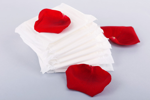 Tampons hygiéniques et pétales de rose sur fond clair
 - Photo, image