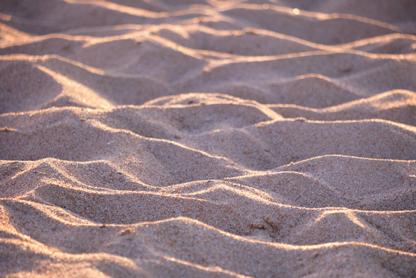 Detailní záběr čisté žluté písečné plochy pokrývající přímořskou pláž osvětlené večerním světlem. Koncept cestování a dovolené - Fotografie, Obrázek