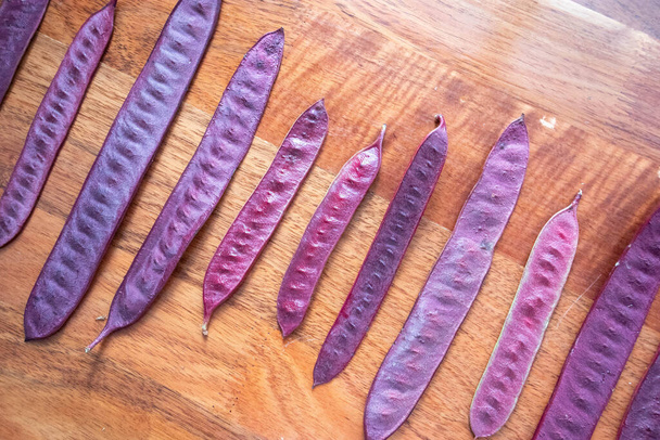 Purple Guaje seed pods are arranged in a pattern on a table. - Φωτογραφία, εικόνα