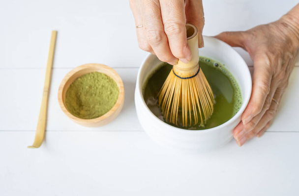 Woman Using Bamboo Whisk to Mix Matcha Green Tea Powder With Water - Фото, изображение