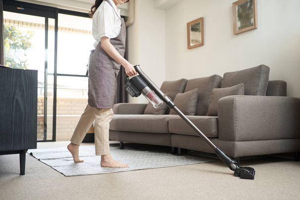 Asian woman vacuuming in the living room - Photo, Image