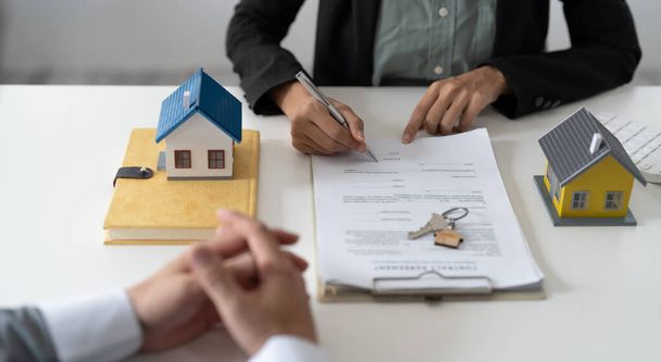 Kiinteistönvälittäjä auttaa asiakasta allekirjoittamaan työsopimuksen talon mallin kanssa - Valokuva, kuva