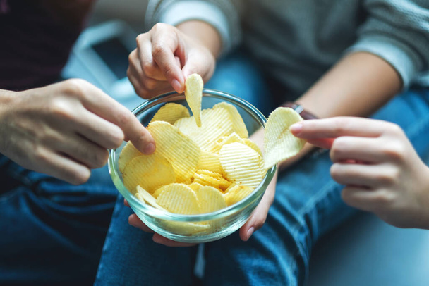 Крупним планом зображення друзів, які діляться і їдять картопляні чіпси на домашній вечірці разом
 - Фото, зображення