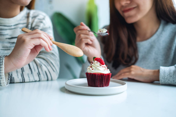 Two women enjoyed eating red velvet cup cake together - Photo, image