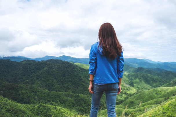 Rear view image of female traveler looking at a beautiful green mountains view - Foto, Imagen