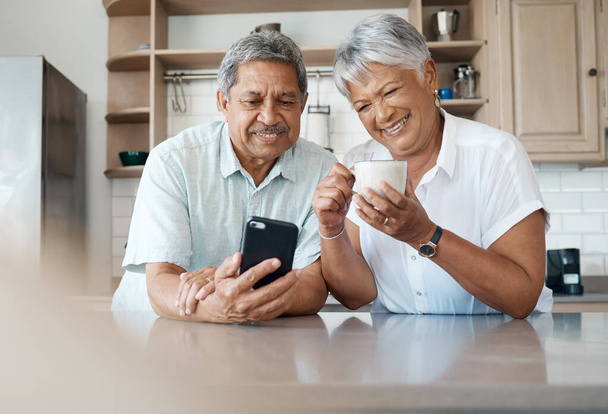 Theyve got the hang of technology. Shot of a senior couple using a phone together at home. - Foto, Imagen
