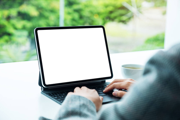 Mockup image of a woman using and typing on tablet keyboard with blank white desktop screen as a computer pc in the office - 写真・画像