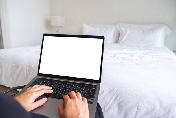 Mockup immagine di una donna che utilizza e digita sul computer portatile con tastiera bianca dello schermo del desktop in camera da letto - Foto, immagini