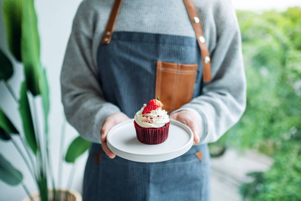 Egy pincérnő, kezében egy darab vörös bársony muffinnal. - Fotó, kép