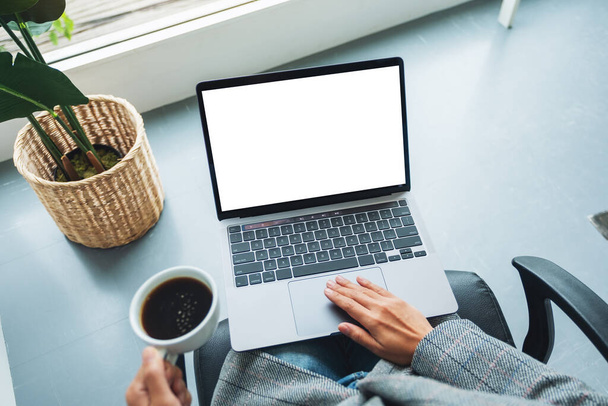 Imagem de maquete de vista superior de uma mulher de negócios usando e tocando no touchpad do laptop com tela de desktop branca em branco no escritório - Foto, Imagem
