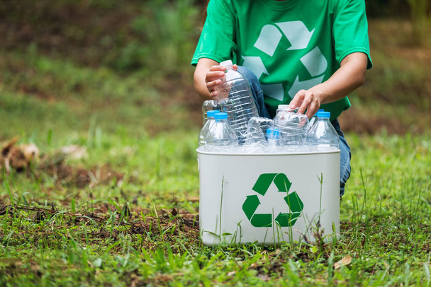 A woman collecting and putting plastic bottles into a recycle bin in the outdoors - 写真・画像