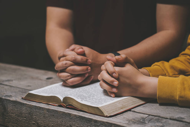 Κοντινό πλάνο δύο χριστιανοί διαβάζουν τη Βίβλο. Χέρια διπλωμένα σε προσευχή σε μια Αγία Γραφή σε ξύλινο τραπέζι. online ομαδική λατρεία, Παγκόσμια ημέρα προσευχής, διεθνής ημέρα προσευχής, ελπίδας, ευγνωμοσύνης, ευγνωμοσύνης, εμπιστοσύνης - Φωτογραφία, εικόνα