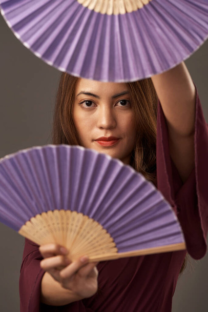 Whats behind your heritage. Cropped portrait of an attractive young woman posing with fans in studio against a grey background. - 写真・画像