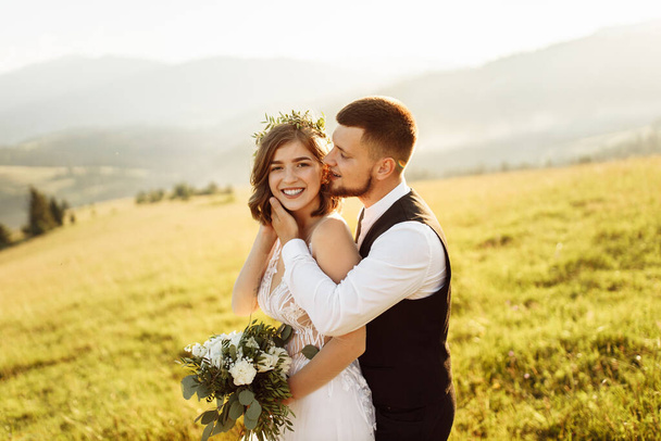 schönes junges verliebtes Hochzeitspaar posiert in den Bergen - Foto, Bild