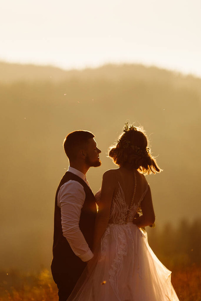 美しい結婚式のカップルは日没時にポーズをとって   - 写真・画像
