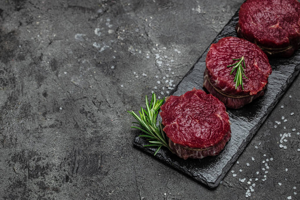 Beef medallions with rosemary and spices, Raw beef meat steak Tenderloin fillet on a dark background. banner, menu, recipe place for text, top view. - Foto, Bild