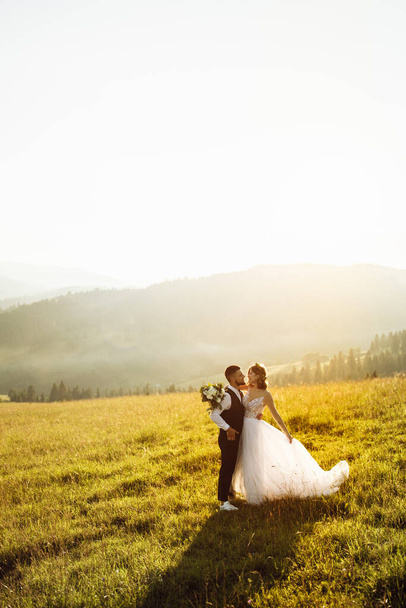 beautiful young wedding couple in love posing on the background of the mountains - Fotó, kép