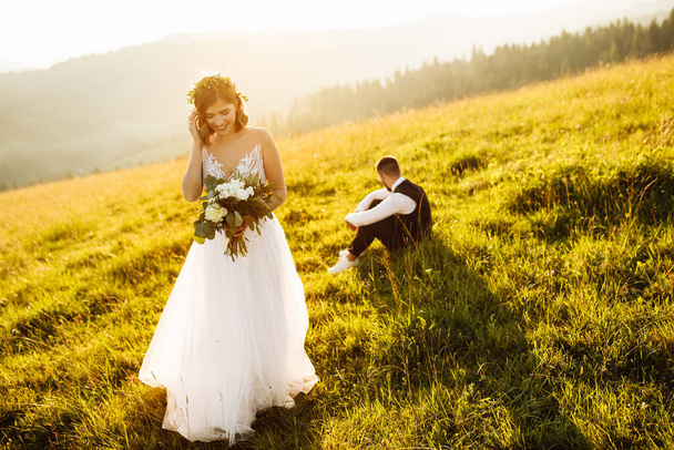 美しい若い結婚式のカップルが山を背景にポーズをとって - 写真・画像