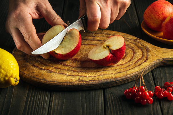Kokki leikkaa omenoita leikkuulaudalla tehdä soseet tai hedelmämehua. Apple ruokavalio joukko vitamiineja. Työympäristö keittiön pöydällä - Valokuva, kuva