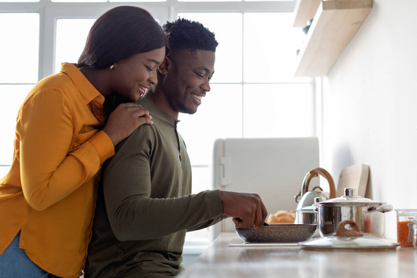 Giovani sposi neri amorevoli che preparano insieme il cibo in cucina - Foto, immagini