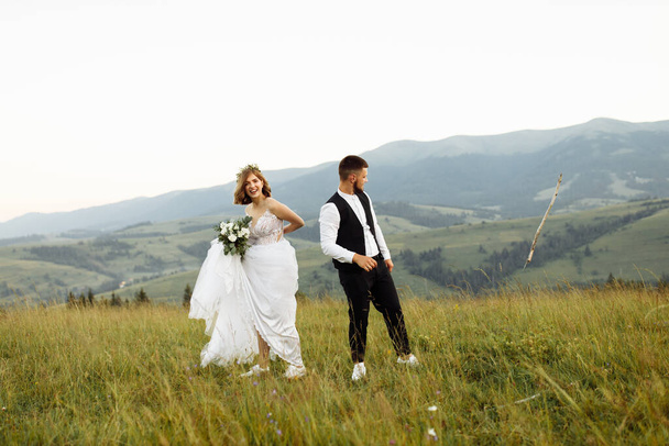 beautiful young wedding couple in love posing on the background of the mountains - Φωτογραφία, εικόνα