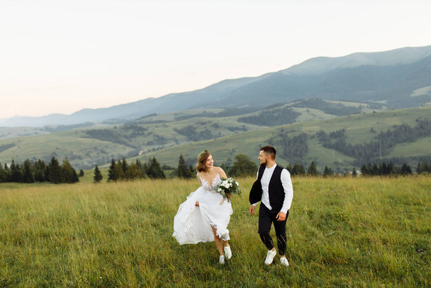 beautiful young wedding couple in love posing on the background of the mountains - Foto, afbeelding