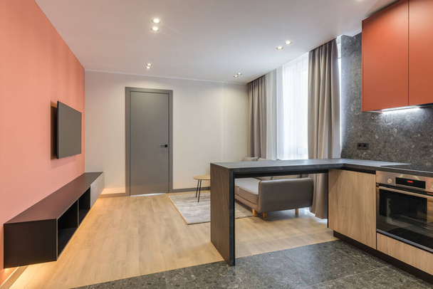 Design moderno de um apartamento residencial com paredes de cor Marsala, um sofá cinza e uma cozinha de madeira - Foto, Imagem